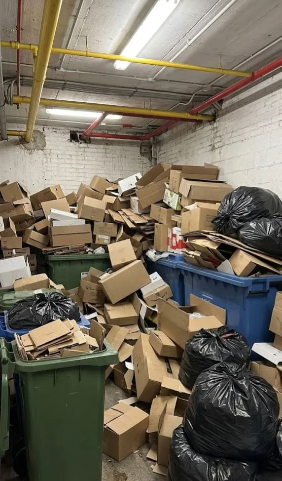 Cuarto de residuos sin gestionar, cartón y bolsas acumuladas
